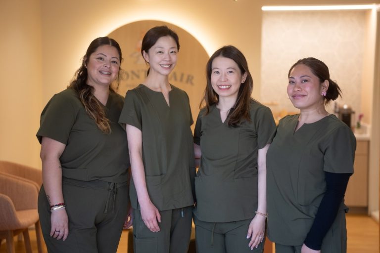 Four women healthcare professionals in uniforms smiling.