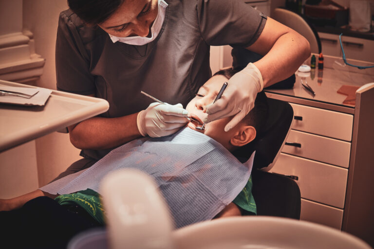 Dentist examines child's teeth in clinic.