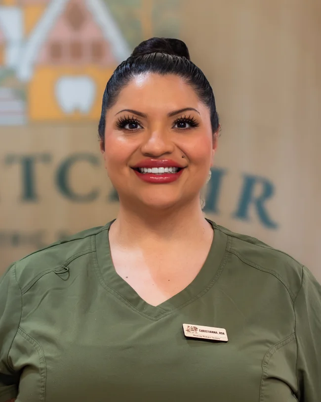 Smiling woman in green uniform with name tag.