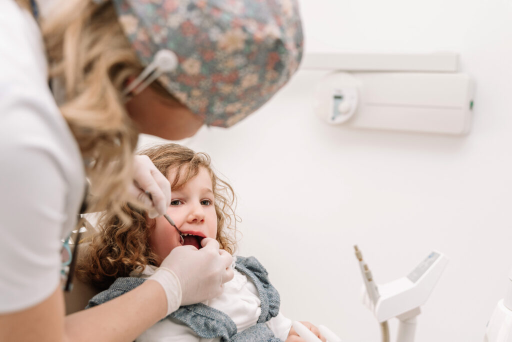 Pediatric dentist examining a young child’s teeth during a gentle first dental visit, showing what parents can expect.