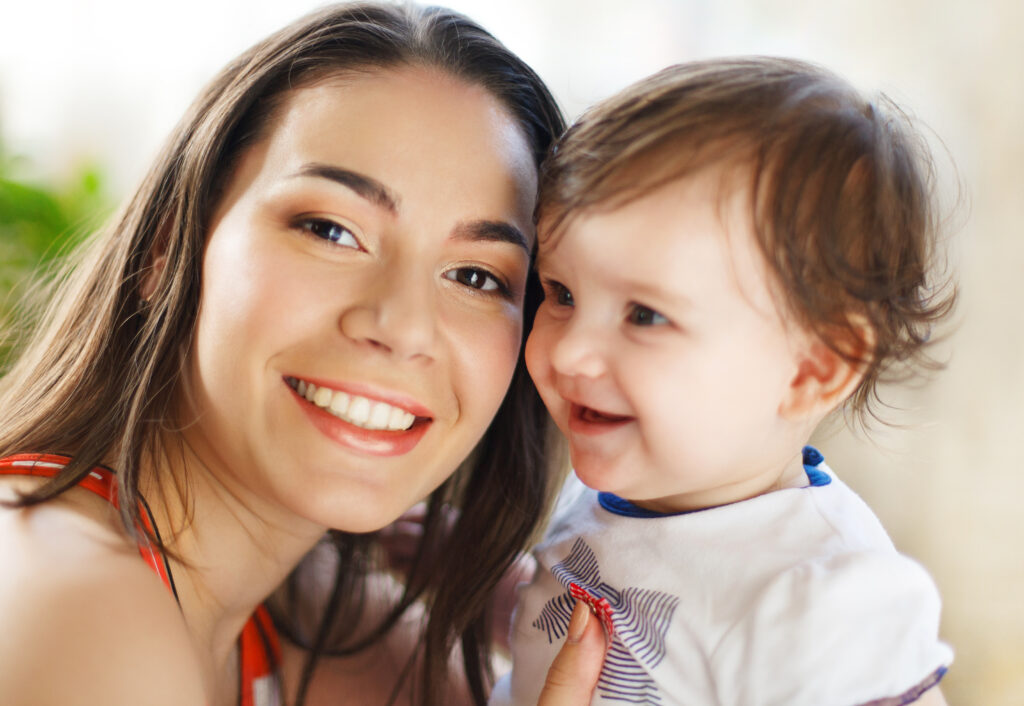 Mother holding her baby during a knee-to-knee dental exam, showing how infants stay secure and calm during their first pediatric dental visit.