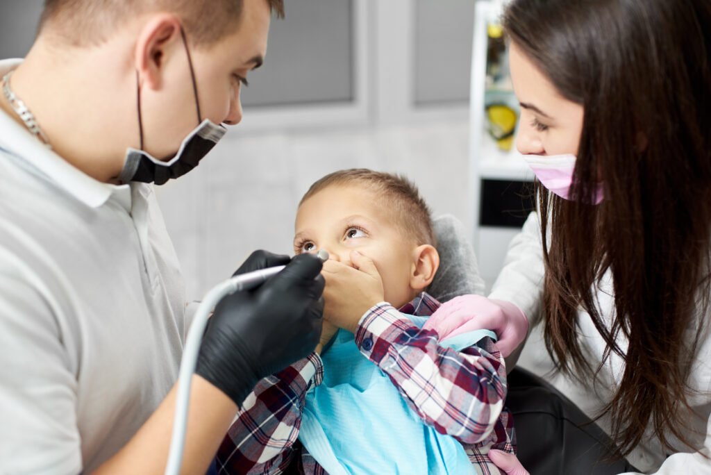 Infant receiving a gentle oral exam during their first preventive pediatric dental visit, with a parent present for comfort